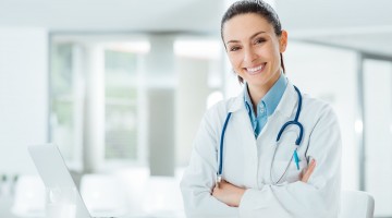 Confident female doctor sitting at office desk and smiling at camera, health care and prevention concept